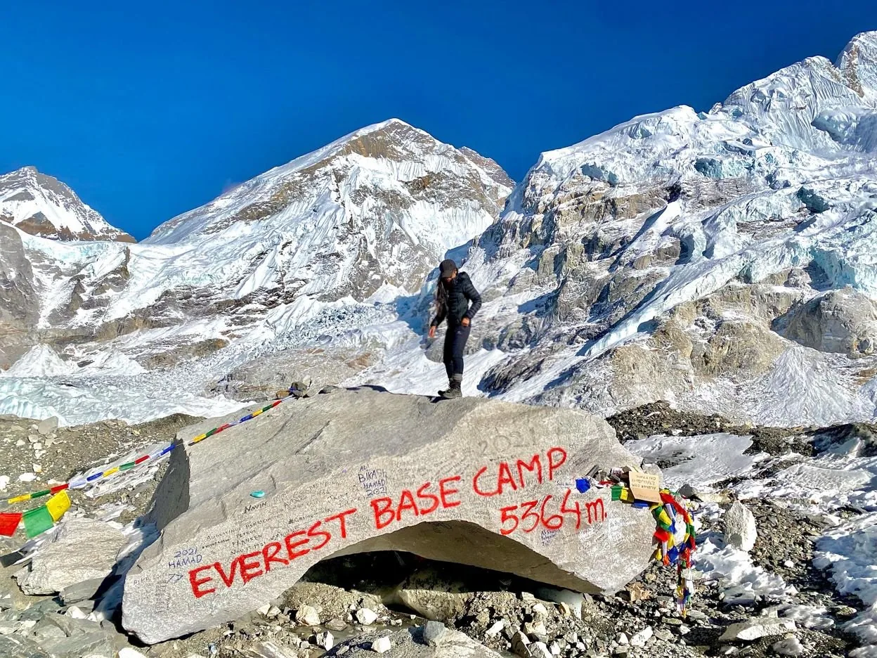 Trekker at Everest Base Camp 5364m sign with Himalayan peaks behind