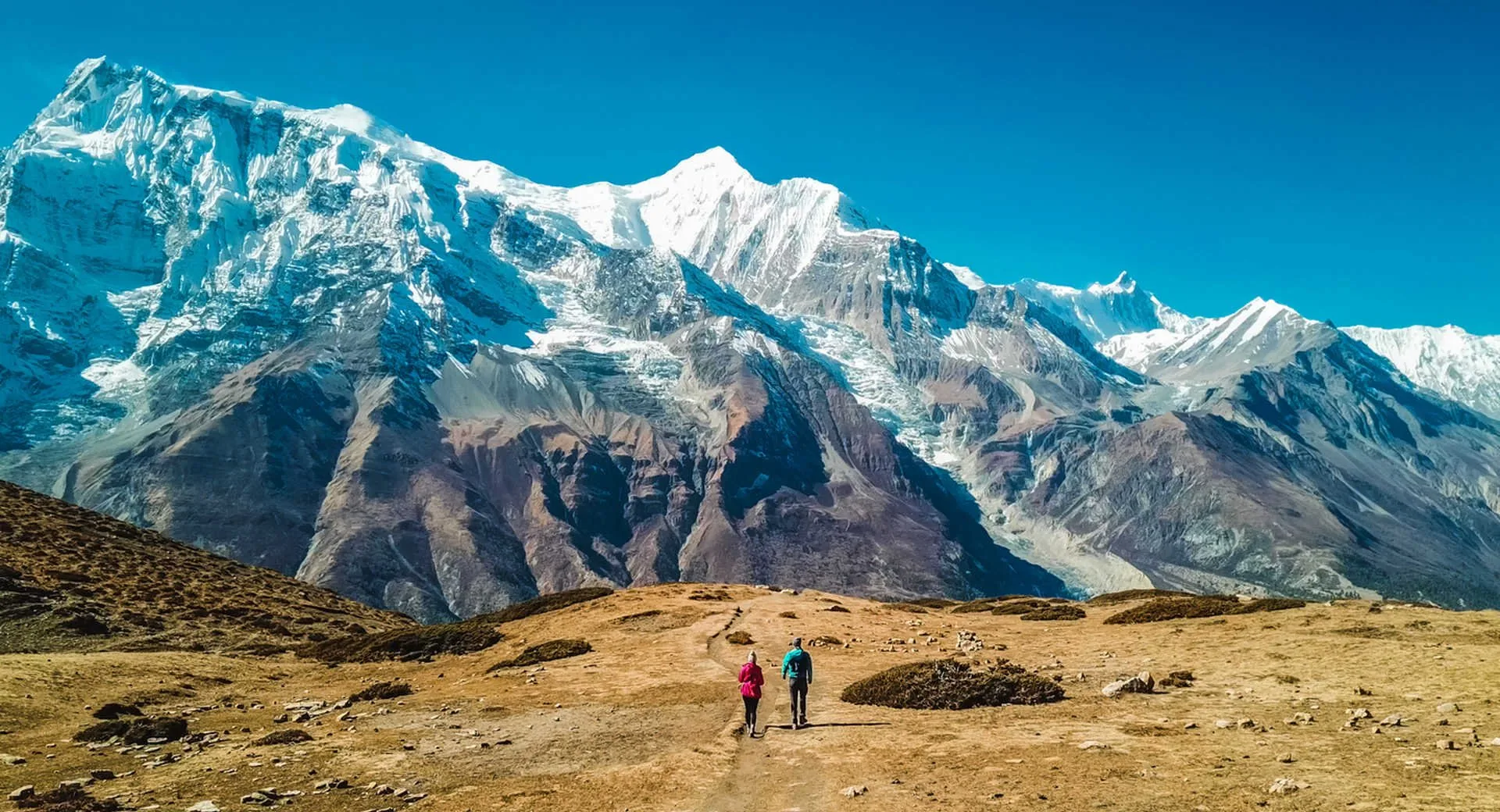 Two trekkers on trail toward snow-capped Annapurna range Nepal