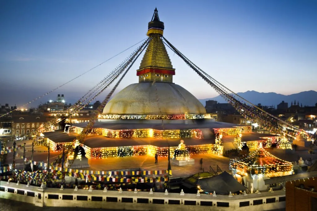 Boudhanath Stupa Kathmandu illuminated at night with prayer flags and golden lights
