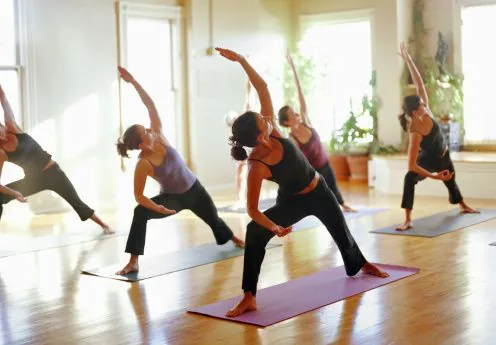 Yoga class practicing side angle pose in a sunlit studio